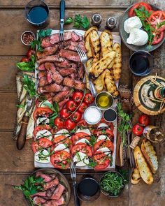 an assortment of food is laid out on a table with utensils and plates