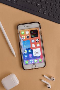 an iphone sitting on top of a desk next to a keyboard and mouse with a pen