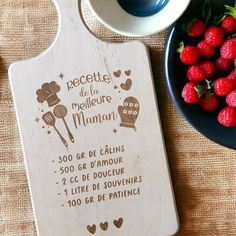 a wooden cutting board sitting on top of a table next to strawberries and berries