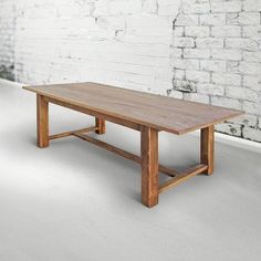 a wooden table sitting in front of a brick wall with white paint on it's walls