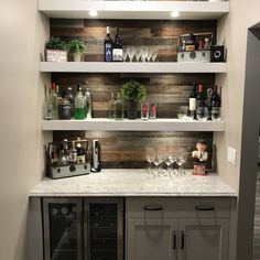 the shelves in this kitchen are filled with wine glasses and liquor bottles, along with other items