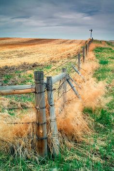 a wooden fence in the middle of a field