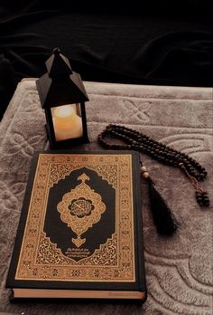 an open book with a lit candle next to it on a tablecloth covered bed