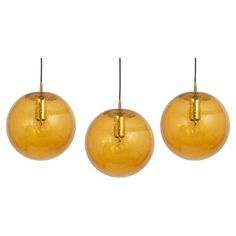 three shiny gold colored ornaments hanging from the top of each ornament on a white background