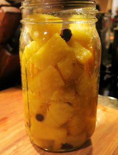 a jar filled with sliced pineapples on top of a wooden table