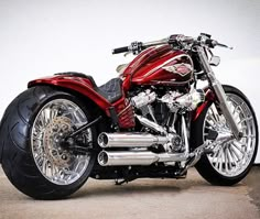 a red and black motorcycle parked on top of a cement floor next to a wall