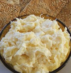 a bowl filled with mashed potatoes sitting on top of a table covered in sesame seeds