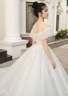 a woman in a white wedding dress is walking down the street with her hand on her hip