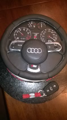 an audi car steering wheel cake on a wooden table with red and black trims