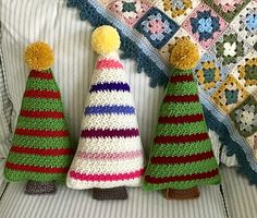 three crocheted christmas trees sitting on top of a couch next to a blanket