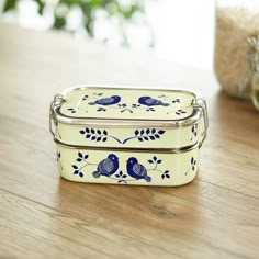 two blue and white tins sitting on top of a wooden table