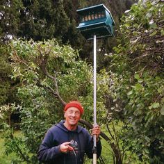 a man in a red hat is holding a bird feeder and posing for the camera