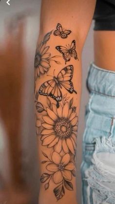 a woman's arm with butterflies and sunflowers tattooed on the side of her arm