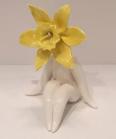 a yellow flower sitting on top of a white table