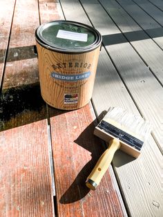 a paint can and brush sitting on a wooden deck