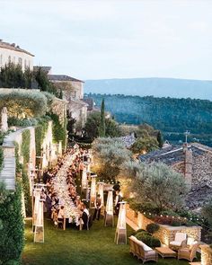 an outdoor dinner is set up on the lawn in front of some buildings and trees