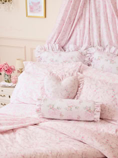 a bed with pink and white comforters, pillows and blankets on top of it