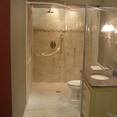 a walk in shower sitting inside of a bathroom next to a white toilet and sink