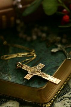 an old book with a cross on it next to some flowers and other items in the background