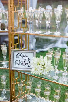 there are many champagne glasses on the shelves and one is filled with white flowers in it