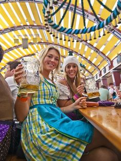 two women sitting at a table with beers in their hands