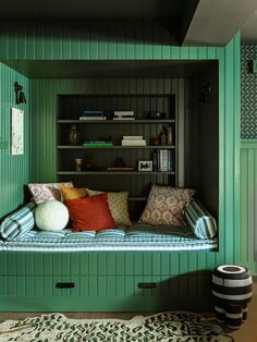 a room with green painted walls and a couch in the corner, surrounded by bookshelves