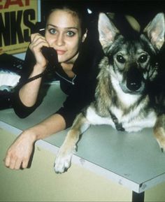 a woman sitting next to a dog on the phone