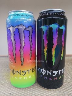 two cans of monster energy drink sitting next to each other on top of a table