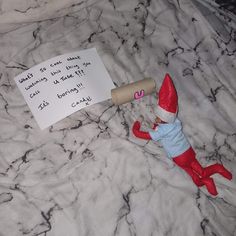 an elf laying on top of a bed next to a note