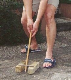 a man is bending over to pick up something from the ground with a shovel and block