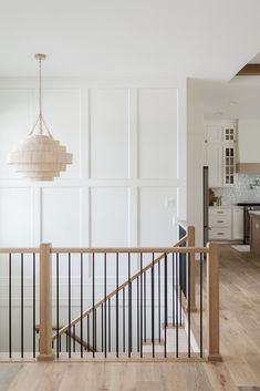 an open living room and kitchen area with wood flooring, white walls and wooden handrails