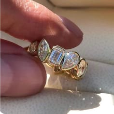 a close up of a person's hand holding a ring with three diamonds on it