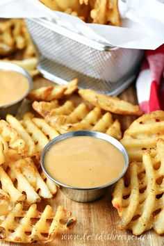 a wooden table topped with french fries and dipping sauce