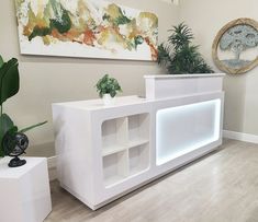 a white reception table with two planters on each side and a painting hanging above it