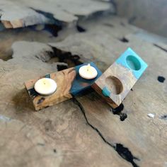 two candles sitting on top of a piece of wood