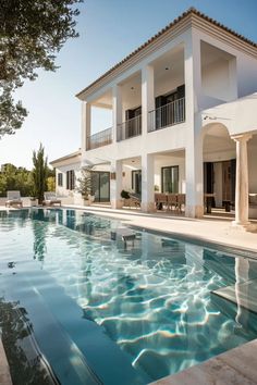 an outdoor swimming pool next to a large white house