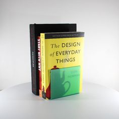 two books sitting next to each other on top of a white table, one is yellow and the other is green