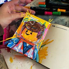 a child's hand is holding an art project with colored crayons