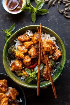 a green bowl filled with chicken and rice next to two small bowls full of sauce