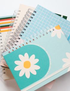 several notebooks stacked on top of each other with flowers in the middle one is empty