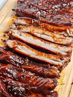 sliced barbecue ribs on a cutting board with bbq sauce