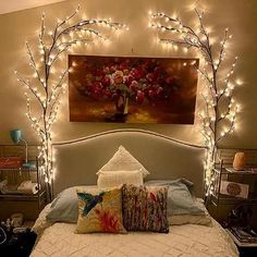 a bed with white sheets and lights on the headboard, along with decorative pillows