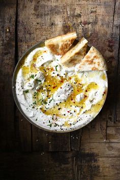 a bowl filled with hummus and pita bread on top of a wooden table