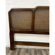 a wooden headboard with wicker panels on it's sides, against a white brick wall