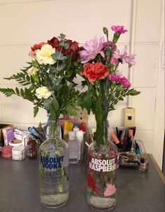 two vases filled with flowers sitting on top of a counter next to each other