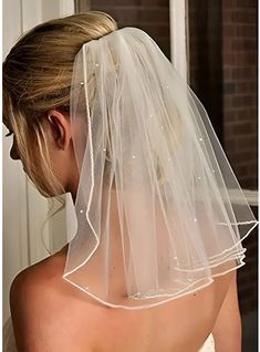 the back of a bride's wedding dress with a veil on her head and shoulder