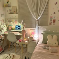 a room with a bed, desk and computer on top of it in front of a window