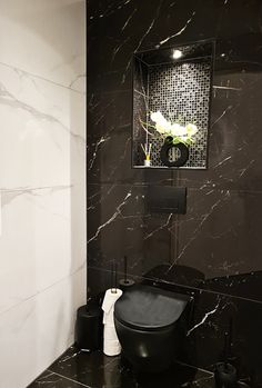 a bathroom with black and white marble walls, flooring and a mirror above the toilet