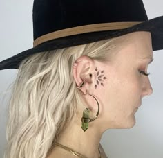 a woman with blonde hair wearing a black hat and ear piercings on her ears