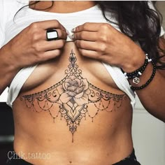 a woman with a rose tattoo on her stomach is holding something in her hand and looking at the camera